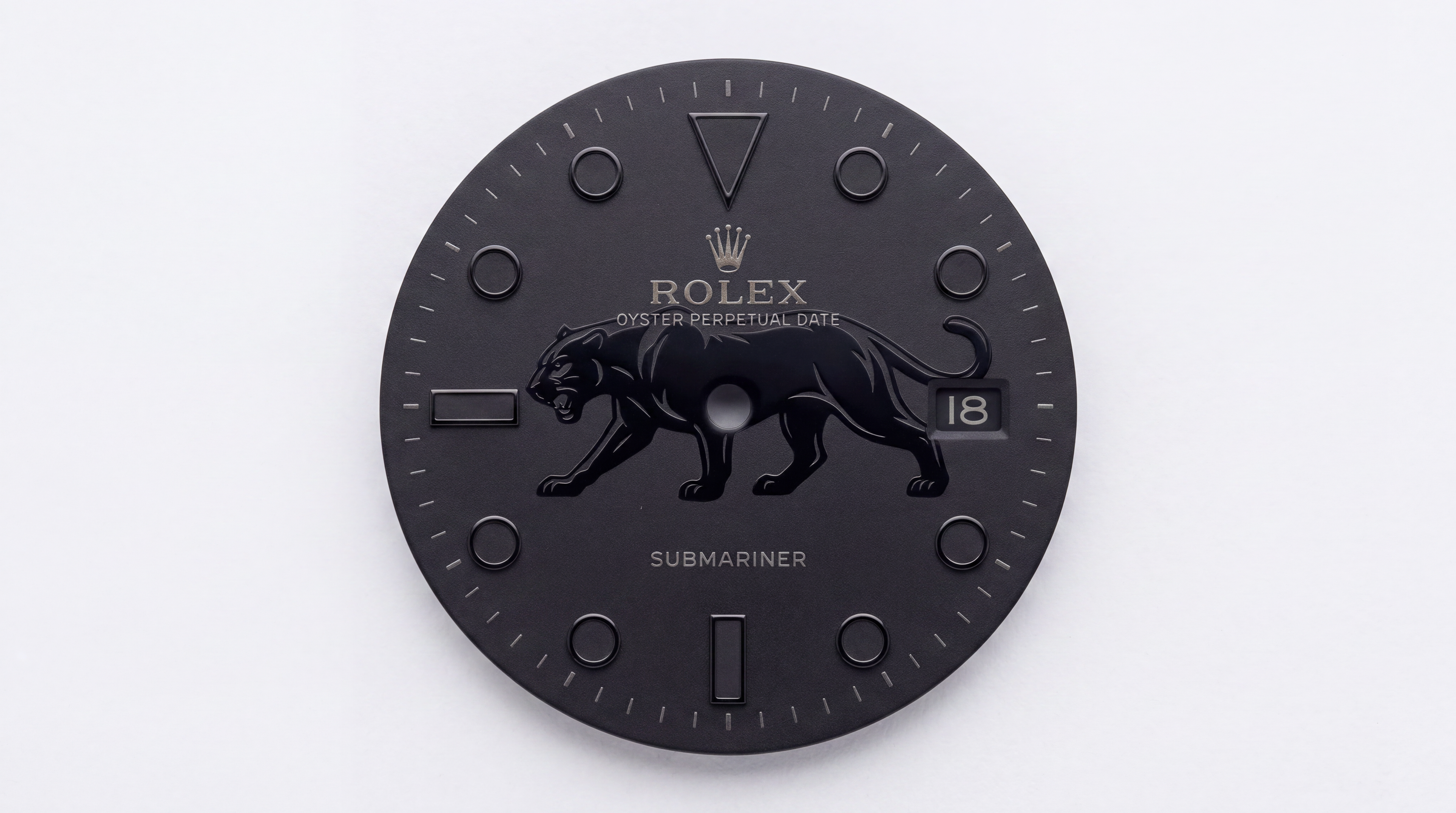 A black Rolex Submariner watch dial or faceplate with an embossed black panther logo, gold-tone Rolex crown and text, and a date window showing 18, photographed against a plain white background.